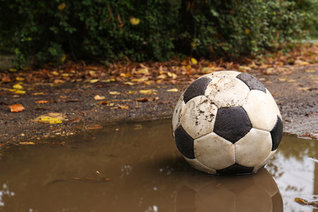 Dirty soccer ball in muddy puddle, space for textの写真素材
