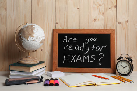 Blackboard with question Are You Ready For Exams? on white table near wooden wallの写真素材