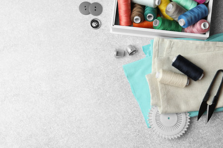 Flat lay composition with spools of threads and sewing tools on light background, space for textの写真素材