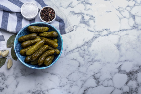 Bowl of pickled cucumbers and ingredients on white marble table, flat lay. Space for textの写真素材