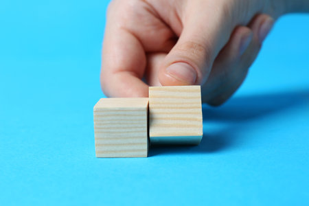 Woman arranging cubes on light blue background, closeup. idea conceptの写真素材