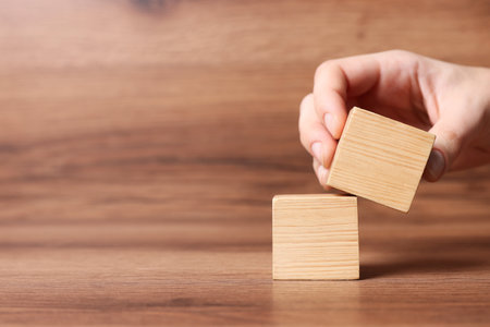 Woman arranging cubes on wooden background, closeup with space for text. idea conceptの写真素材