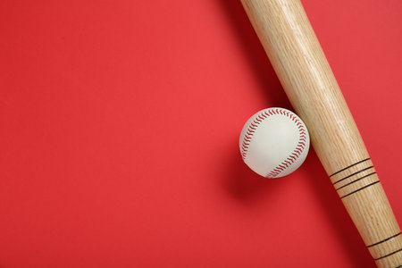 Wooden baseball bat and ball on red background, flat lay. Space for textの写真素材