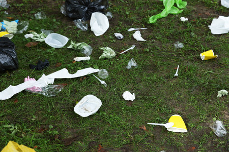 Different garbage scattered on green grass outdoorsの写真素材