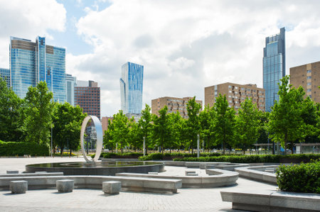 Beautiful fountain near buildings in city under cloudy skyの写真素材