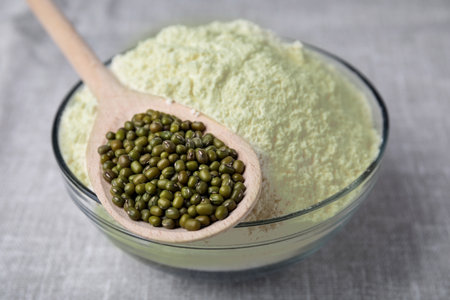 Bowl of flour, spoon and mung beans on light gray cloth, closeupの写真素材