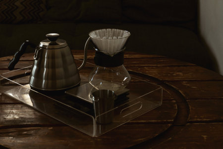 Cup with coffee, wave dripper and kettle on wooden table in cafe