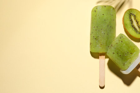 Tasty kiwi ice pops and space for text on pale light beige background, top view.の写真素材