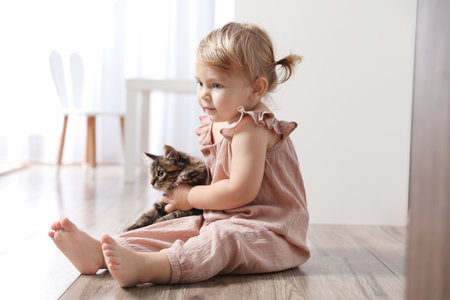 Cute little child with adorable pet on floor at homeの写真素材