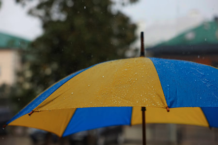 Yellow and blue umbrella outdoors on rainy day, closeup