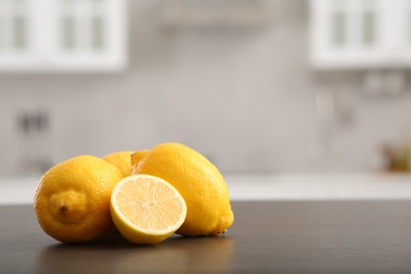 Whole and cut lemons on wooden counter in kitchen, space for textの写真素材