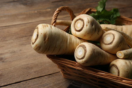 Wicker basket with delicious fresh ripe parsnips on wooden table, closeupの写真素材