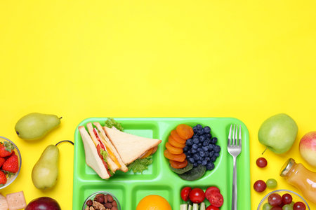 Flat lay composition with serving tray and tasty healthy food on yellow background. Space for textの写真素材