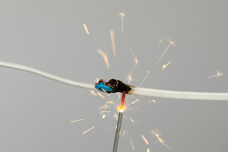 Inflamed white wire on gray background, closeup. Electrical short circuit