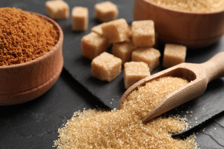 Scoop with brown sugar on black table, closeupの写真素材
