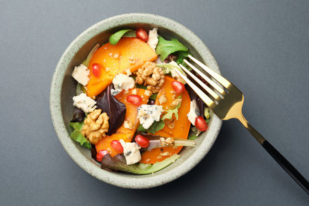 Delicious persimmon salad with cheese and pomegranate on gray table, top viewの写真素材