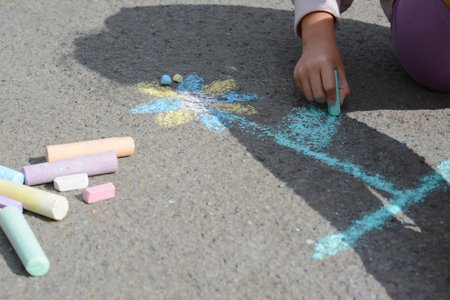 Little child drawing flower with chalk on asphalt, closeupの写真素材