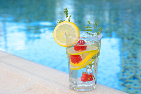 Delicious refreshing lemonade with raspberries near swimming pool