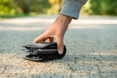 Man picking lost wallet from ground outdoors, closeup. Space for textの写真素材