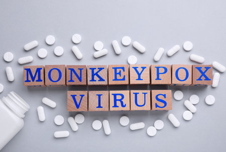Words Monkeypox Virus made of wooden cubes and pills on light background, flat lay
