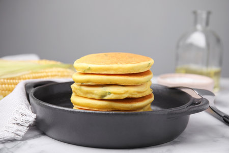 Tasty corn pancakes served on white marble table
