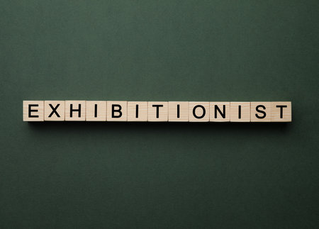 Word EXHIBITIONIST made with wooden cubes on dark green background, flat lay