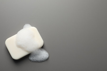 Soap with fluffy foam on gray background, top view. Space for textの写真素材