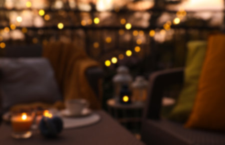 Blurred view of garden furniture with pillow, soft blanket and burning candles at balconyの写真素材