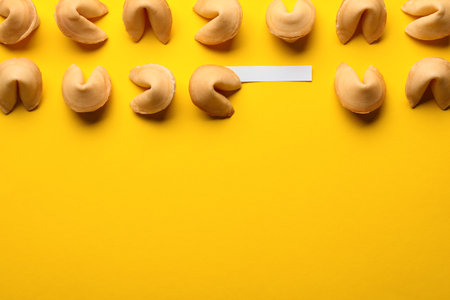 Many tasty fortune cookies with predictions on yellow background, flat lay. Space for textの写真素材