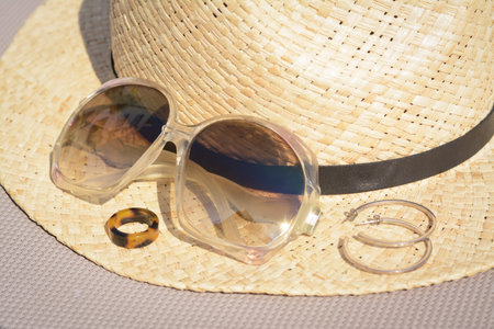 Stylish hat, sunglasses and jewelry on gray surface, closeup