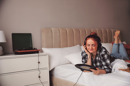 Young woman listening to music with turntable in bedroomの写真素材