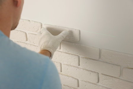 Worker installing decorative wall tiles in room, closeupの写真素材