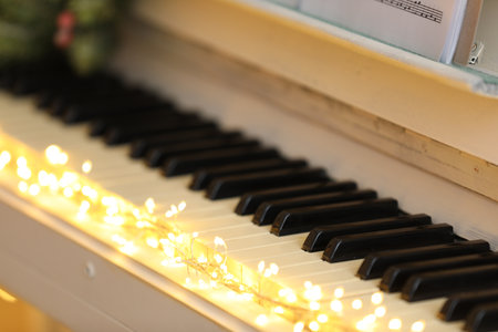 Glowing fairy lights on piano keys, closeup. christmas musicの写真素材
