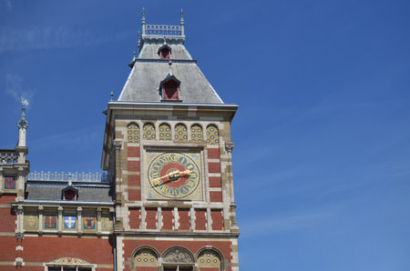 Beautiful building of central railway station with clock against blue sky, low angle view. Space for...