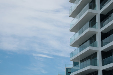 Exterior of residential building with balconies against blue sky, low angle view. Space for textの写真素材