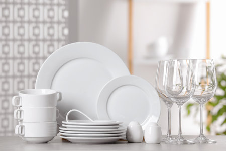Set of clean dishware and glasses on light gray tableの写真素材