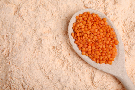 Spoon with lentil grains on flour, top view. Space for textの写真素材