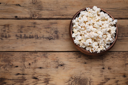 Bowl of tasty popcorn on wooden table, above view. Space for textの写真素材
