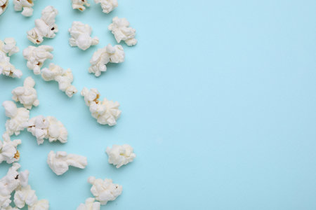 Tasty popcorn on light blue background, flat lay. Space for textの写真素材