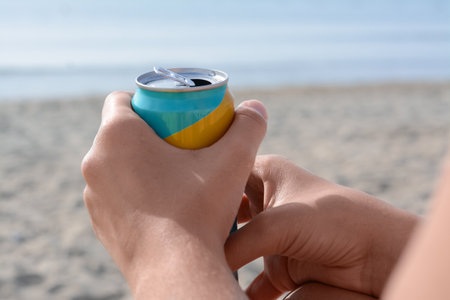Woman holding aluminum can with beverage on beach, closeupの写真素材