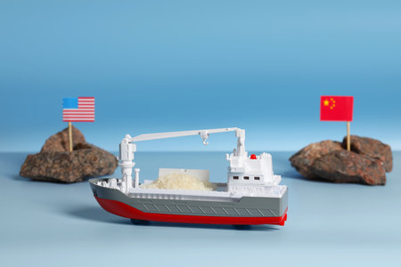 Toy cargo vessel, stones with American and Chinese flags on color background. export concept