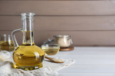 Jug of organic sesame oil on white wooden table. Space for textの写真素材
