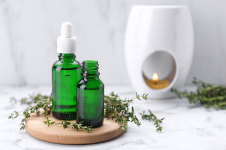 Thyme essential oil on white marble table, space for textの写真素材