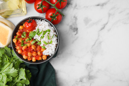 Delicious chickpea curry in bowl on white marble table, flat lay. Space for textの写真素材