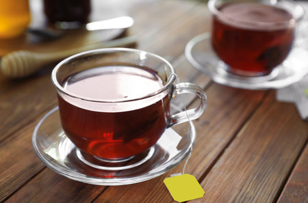 Tea bag in glass cup on wooden table, closeup. Space for textの写真素材