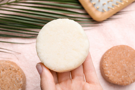 Woman holding solid shampoo bar at pink table, closeup. hair careの写真素材