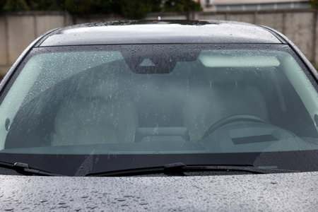 Car wipers cleaning water drops from windshield glass outdoors, closeupの写真素材