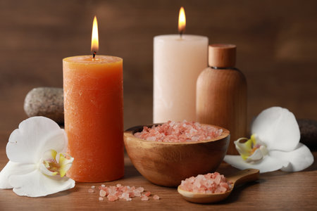 Beautiful spa composition with sea salt, burning candles and flowers on wooden table, closeupの写真素材