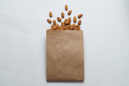 Paper bag with delicious almonds on white background, top viewの写真素材