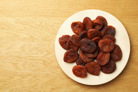 Plate of tasty apricots and space for text on wooden table, top view. dried fruitsの写真素材